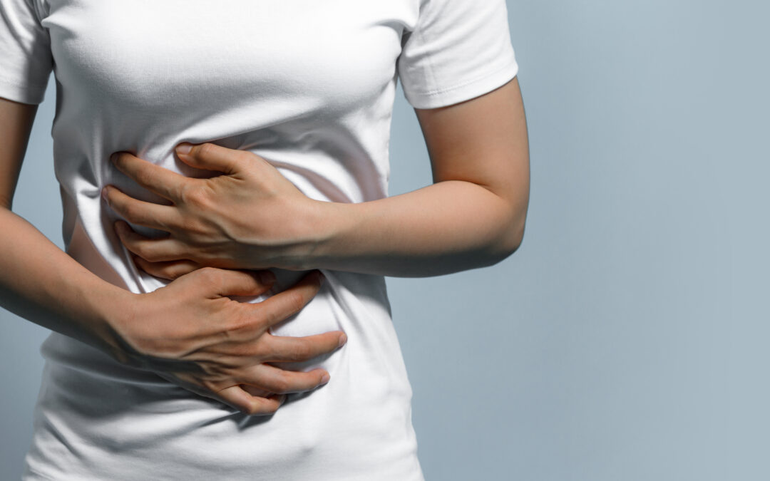 Woman holding her abdomen in visible discomfort, showing signs of stomach or upper abdominal pain possibly related to indigestion or pancreatitis.