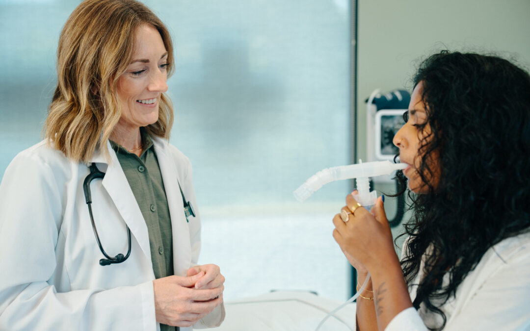 Female medical provider administering breathing treatment to young adult female patient in urgent care clinic room.